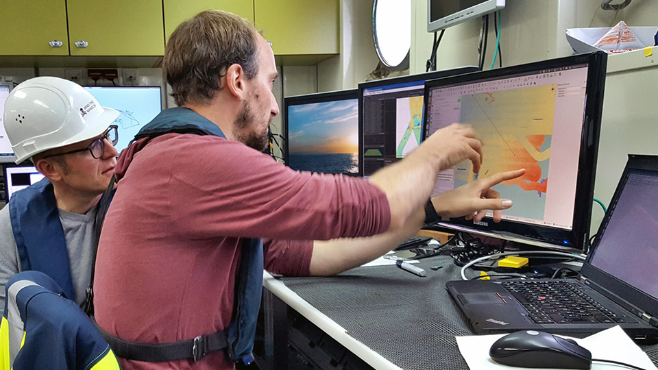 In the dry lab, Dr. Christian Winter (left) and Knut Krämer discuss the results of the multibeam echosounder mapping. Photo: MARUM – Center for Marine Environmental Sciences, University of Bremen; Gabriel Herbst