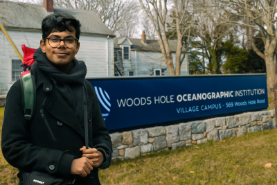 Palash next to the sign of the WHOI Village Campus