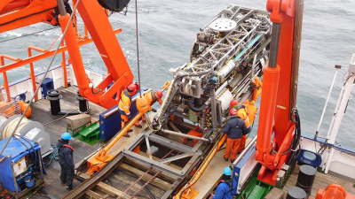 After hav­ing been re­covered by the deck crew, sea floor drill rig MARUM-MeBo slides on a rail sys­tem to its po­s­i­tion on deck for un­load­ing of the core bar­rels. Photo: MARUM - Center for Marine Environmental Sciences, University of Bremen; G. Bohr