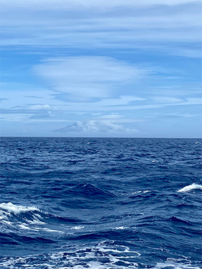 Links im Bild scheint die Flanke von der Hauptinsel Tristan da Cunha durch die Wolkendecke hindurch. Der Umriss des kegelförmigen Vulkans lässt sich vermuten. Foto: Janne Scheffler