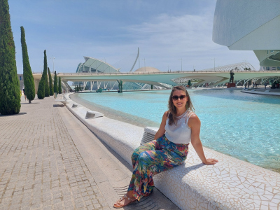 Sofía sitting next to a pool of water which is part of a white modern architecture building