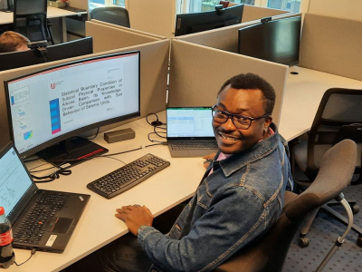 Opeyemi sitting at his desk at NGI in front of a computer screen