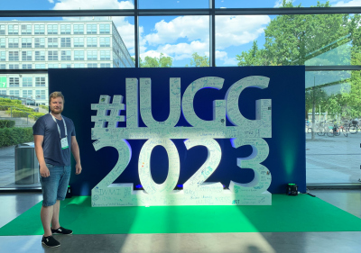 Ilmat standing next to a person-size logo of the IUGG 2023