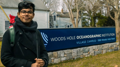 Palash next to the sign of the WHOI Village Campus
